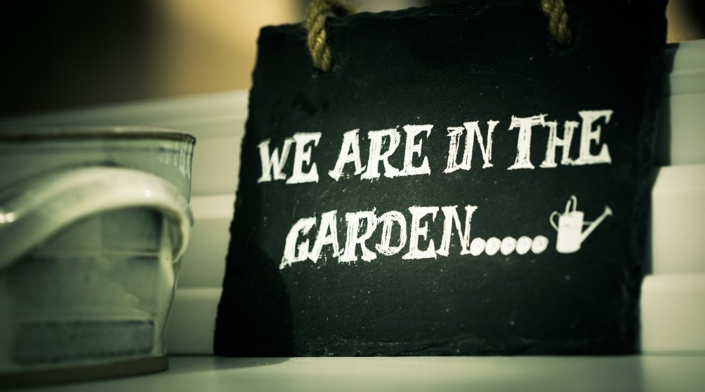 Slate board with 'We are in the Garden...' written on in white paint