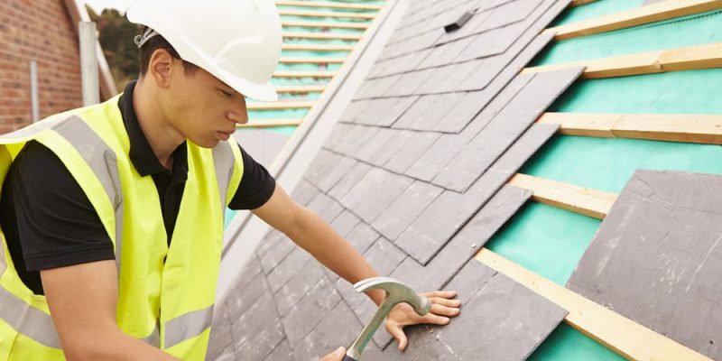 man laying slate roof tiles